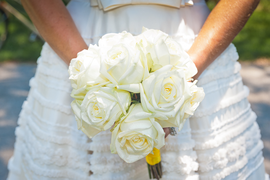Bride holding white roses bouquet at park