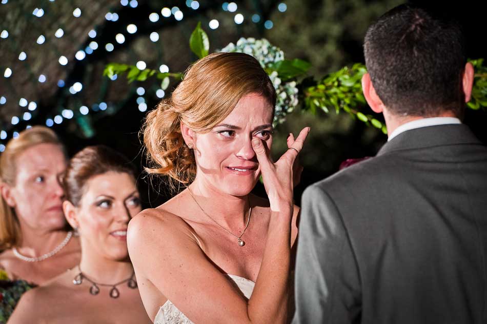 Emotional bride crying and wiping away tears during ceremony