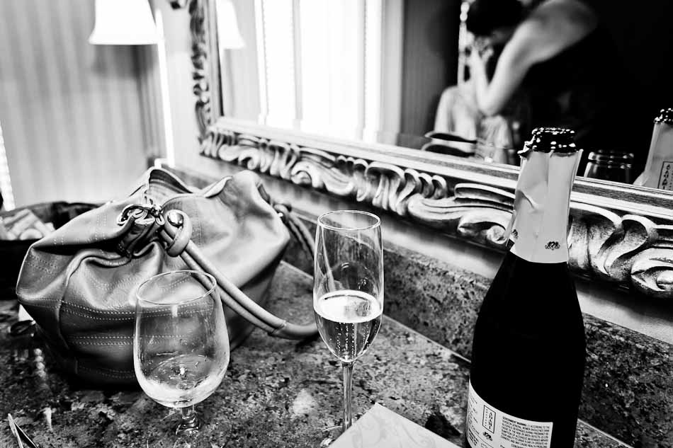 Black and white photo of bride getting ready - mirror, champagne and glasses