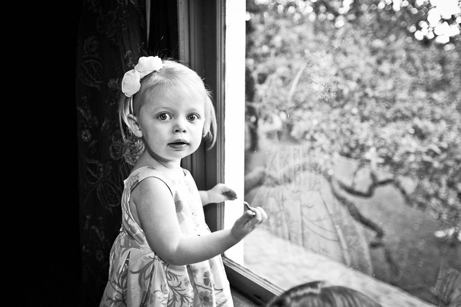 Young child girl standing in front of the window while bride gets ready for ceremony