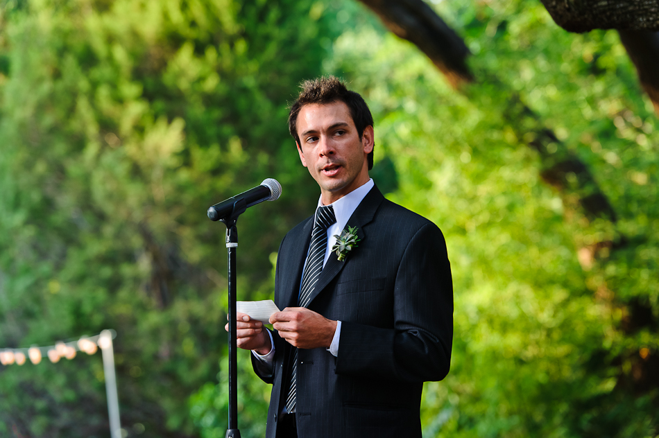 Brother in front of microphone reading poem to wedding couple