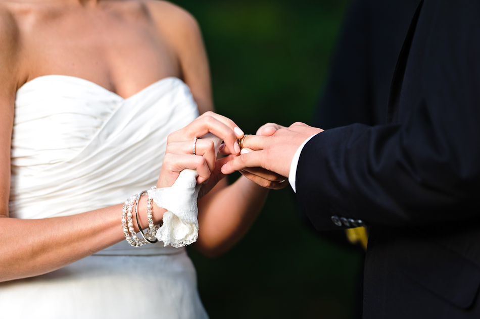 Close-up shot of bride placing ring on groom during ceremony