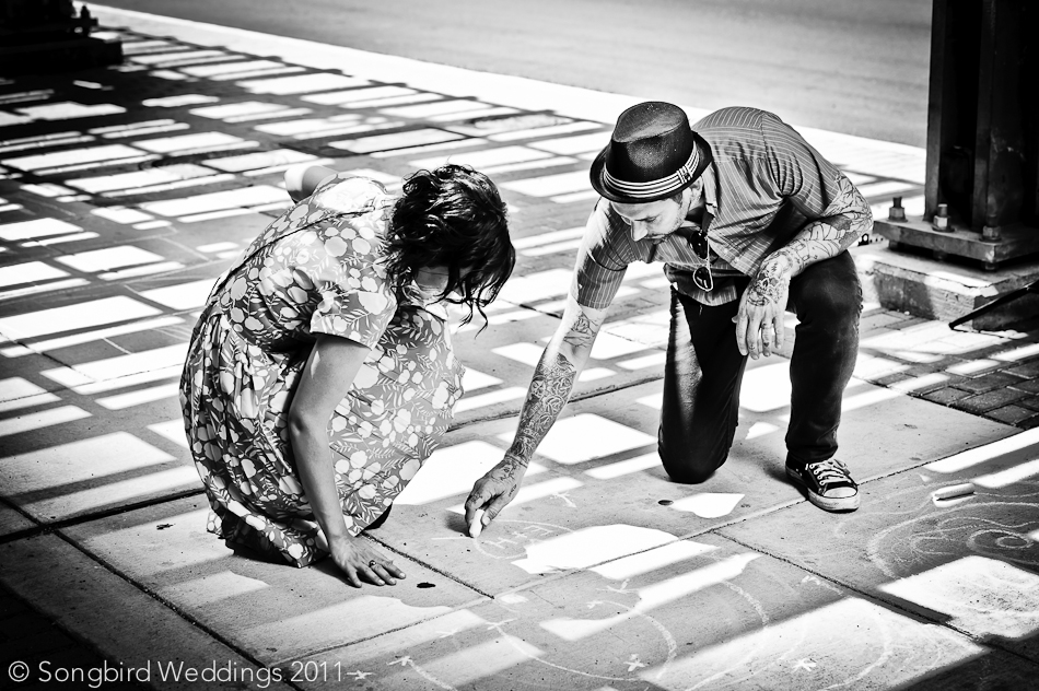 Couple writing their initials in chalk on the sidewalk in front of Austin Childrens Museum.