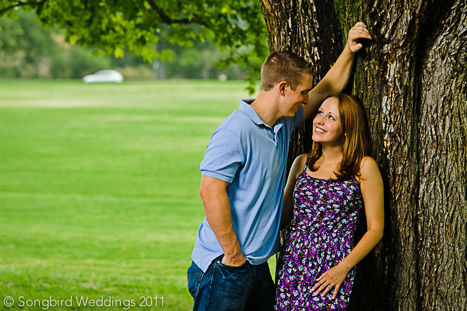 Close-up shot of couple leaning against tree
