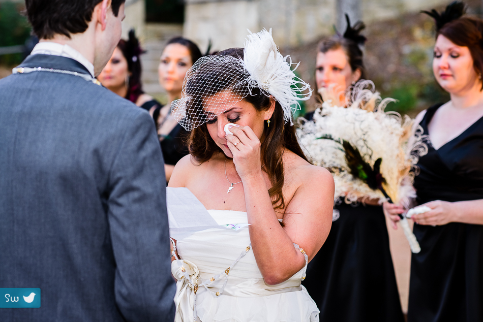 bride during ceremony with white peacock veil crying