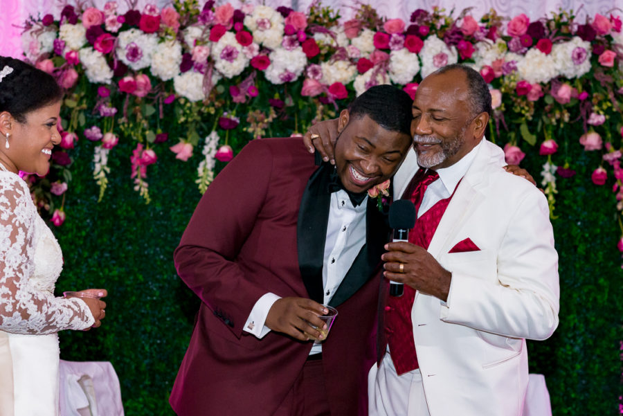 African American wedding toast with pink flower wall by austin wedding photographers