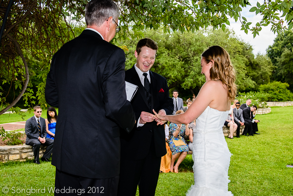 groom placing ring on bride during wedding ceremony at zilker botanical gardens