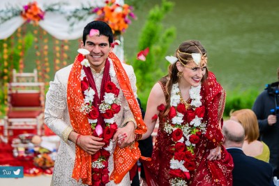 Guests throwing rose petals at bride and groom during Indian Hindu wedding ceremony