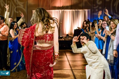 Groom taking photo of bride while dancing during Indian Hindu wedding reception