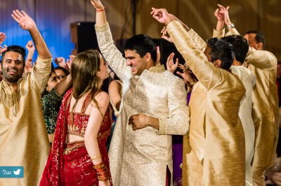 Bride wearing red sari and groom dancing at Indian wedding reception at Hyatt Lost Pines