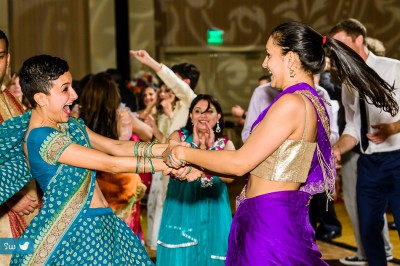 Women dancing at indian wedding reception wearing sarees