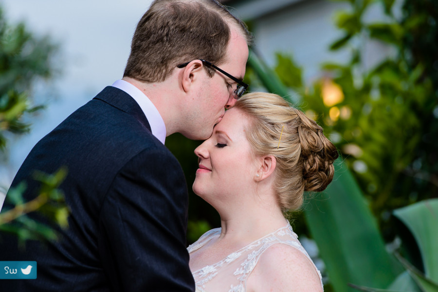 Groom kissing bride by Austin Wedding Photographer at Barr Mansion