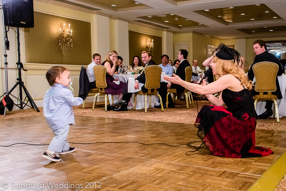 singer performing at wedding reception with child walking across stage