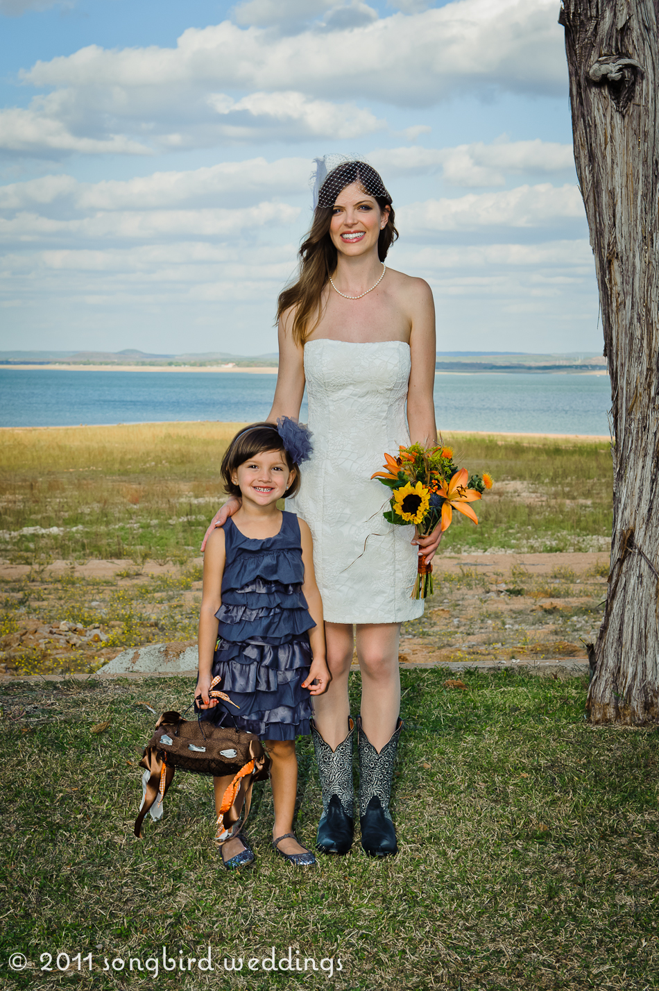 Family portrait of bride with child next to lake holding bouquet